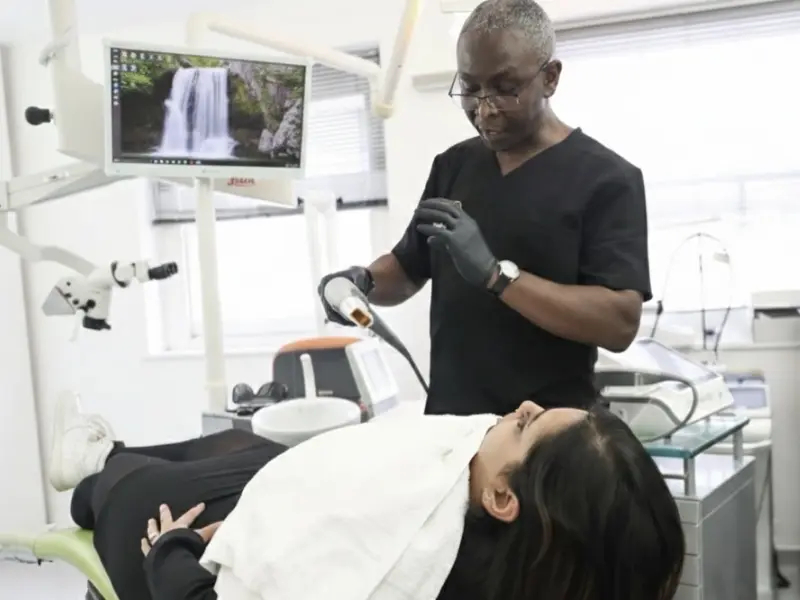 Dr Jamal Johnston in his dental clinic prepares to give young woman high intensity focused treatment